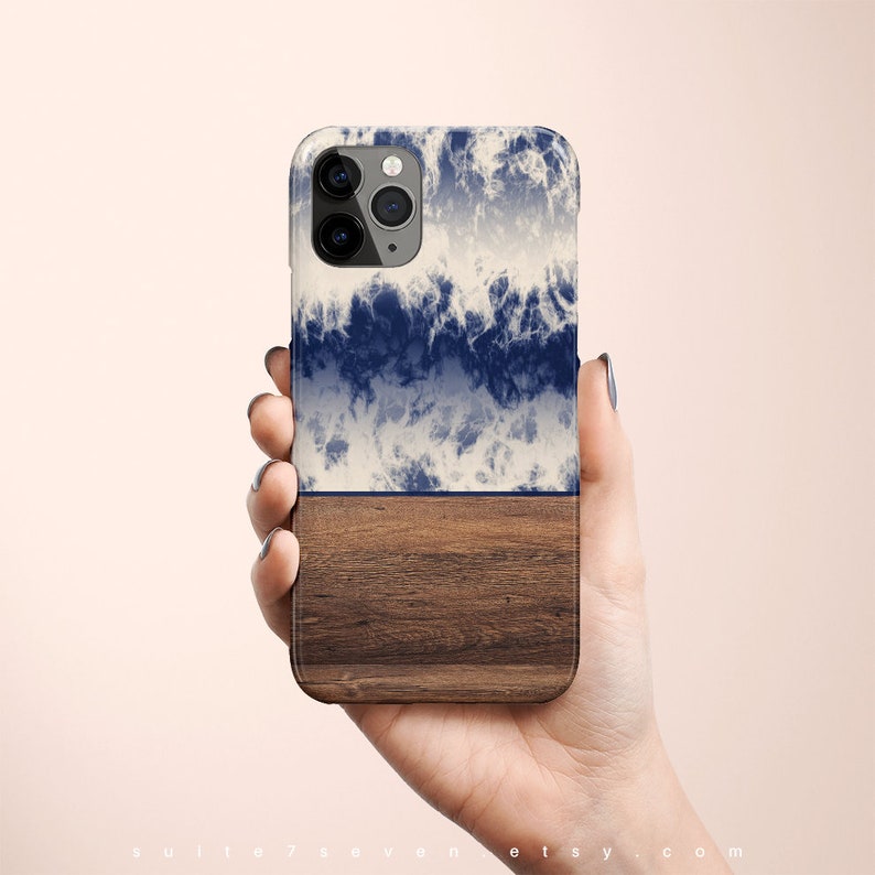May include: A blue and white tie-dye phone case with a wood grain bottom. The case is designed for an iPhone with a triple lens camera.