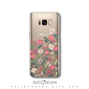 Puede incluir: Una funda transparente para tel&eacute;fono con un dise&ntilde;o floral que presenta flores rosas y blancas, hojas verdes y peque&ntilde;as bayas rojas. La funda est&aacute; dise&ntilde;ada para un tel&eacute;fono Samsung y tiene el logotipo de Samsung impreso en la parte posterior.