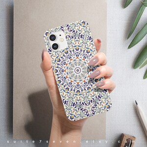 May include: A white iPhone case with a colorful mandala design. The design features blue, green, yellow, and orange colors. The case has a cutout for the camera lens.