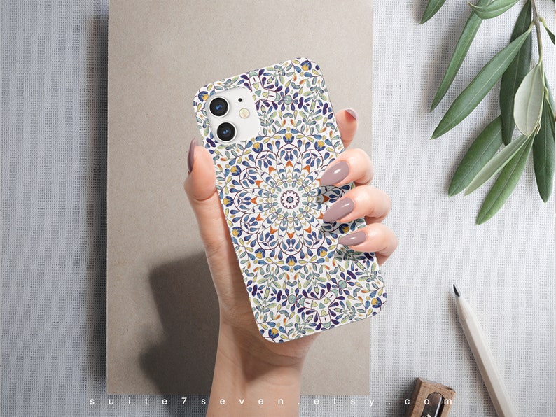 May include: A white iPhone case with a colorful mandala design. The design features blue, green, yellow, and orange colors. The case has a cutout for the camera lens.