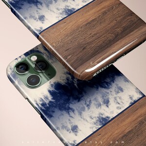 May include: A blue and white tie-dye phone case with a wood accent. The case has a raised camera bump and a cutout for the charging port.