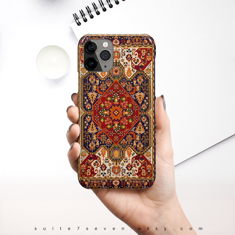 May include: A phone case with a colorful, intricate design inspired by a traditional Persian rug. The case features a central diamond shape with floral and geometric patterns in shades of red, blue, yellow, and white.