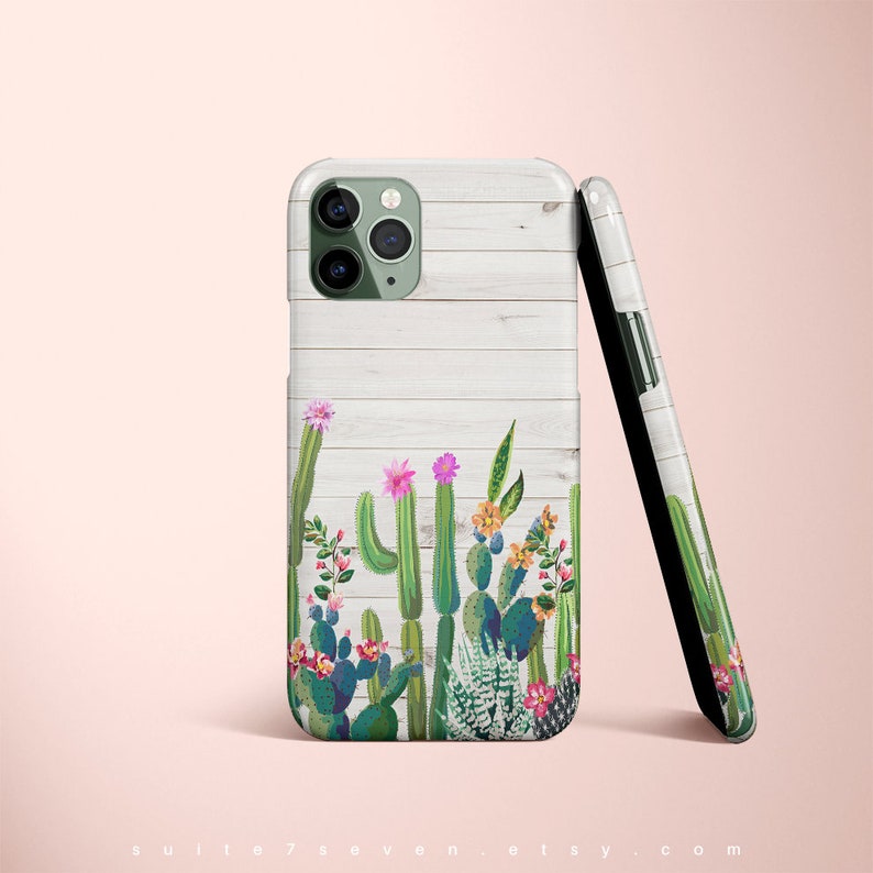 May include: A white phone case with a wood grain pattern and a green cactus design. The case has a cutout for the camera lens.