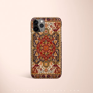 May include: A phone case with a colorful, intricate pattern reminiscent of a Persian rug. The case features a dark blue background with red, orange, and yellow accents. The pattern is symmetrical and includes floral motifs.