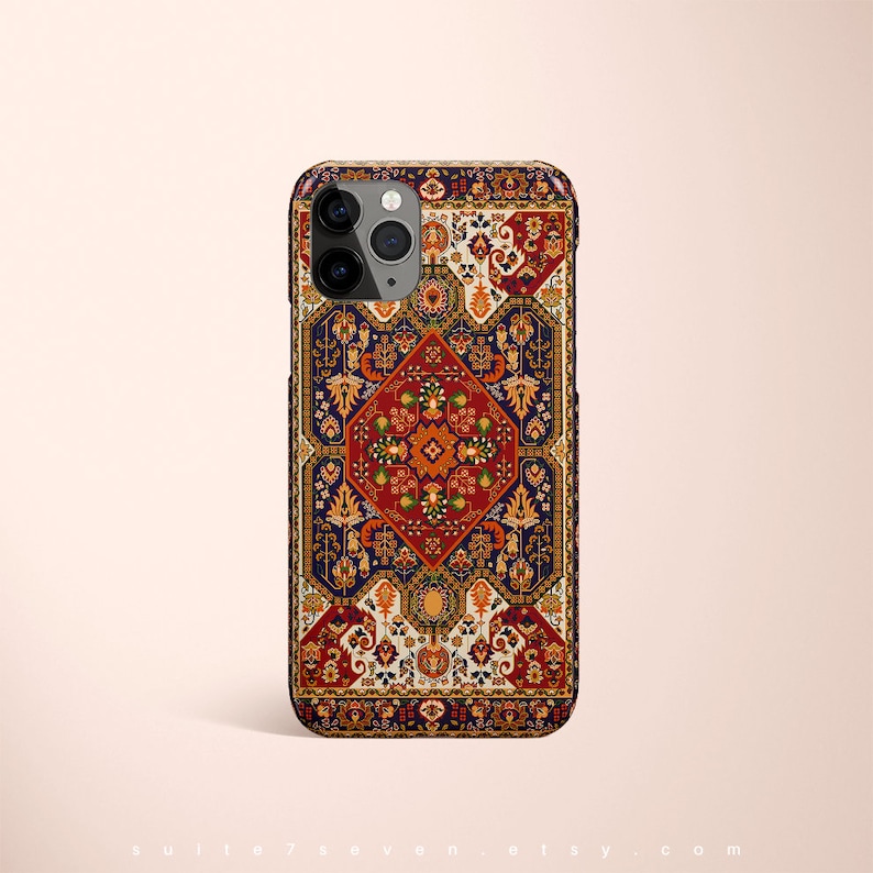 May include: A phone case with a colorful, intricate pattern reminiscent of a Persian rug. The case features a dark blue background with red, orange, and yellow accents. The pattern is symmetrical and includes floral motifs.