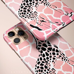 May include: Pink and white phone case with a black and white giraffe print. The case has a raised camera bump and a cutout for the phone's charging port.