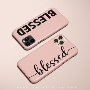 Puede incluir: Dos fundas de iPhone rosas con la palabra "blessed" escrita en negro. Una funda tiene la palabra en mayúsculas y la otra funda tiene la palabra en cursiva.