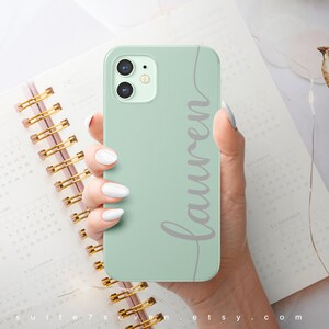 May include: A mint green phone case with a white inscription that says "Lauren".