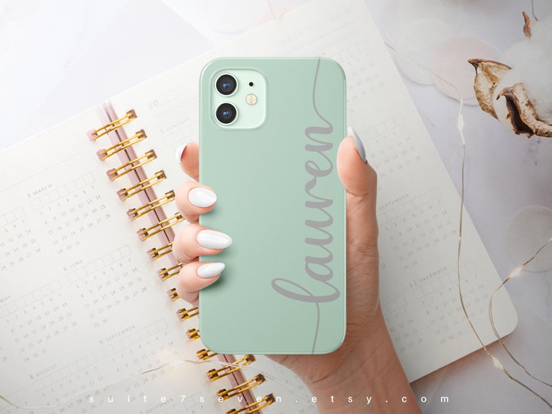 May include: A mint green phone case with a white inscription that says "Lauren".