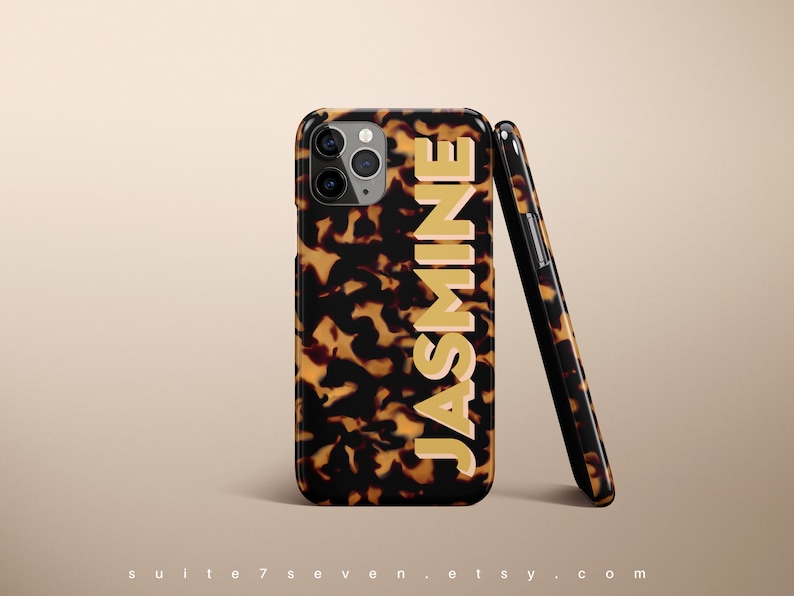 May include: A brown and black tortoiseshell iPhone case with a gold "JASMINE" name printed on the back.