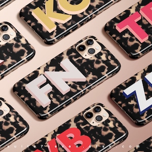 May include: A set of ten phone cases with a tortoiseshell pattern and colourful, oversized letters. The letters spell out the names "KB", "KO", "TB", "FN", "ZB", "AB", "KB", "KO", "TB", and "FN".