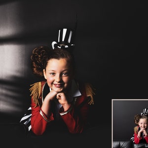 Peut inclure: Une jeune personne portant un costume de ma&icirc;tre de c&eacute;r&eacute;monie rouge et noir avec un chapeau haut de forme noir et blanc. Elle est assise sur une surface noire et sourit &agrave; la cam&eacute;ra.