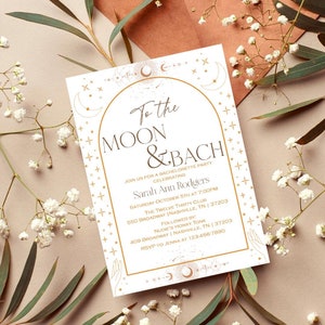 May include: A white invitation with gold lettering for a bachelorette party. The invitation says "To the Moon & Bach" and includes the bride's name, date, time, and location. The invitation is decorated with a crescent moon and stars.