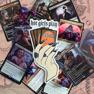 May include: A sticker of a hand holding a deck of playing cards. The sticker is white with a black outline and features a hand with long, sharp nails. The text "hot girls play" is printed in black on the sticker. The sticker is surrounded by various Magic: The Gathering cards.