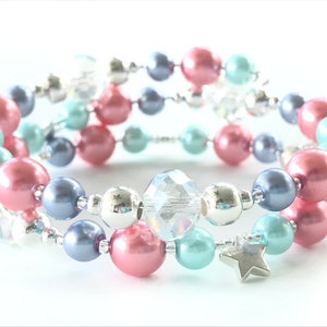 May include: A multi-strand bracelet featuring pink, blue and silver beads. The bracelet includes a clear crystal bead and a silver star charm.