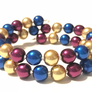 May include: A triple-strand beaded bracelet with gold, burgundy, and blue beads.