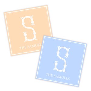 May include: Two square coasters, one peach and one light blue, each featuring a white ornate letter "S" and the text "THE SAMUELS" in a serif font. The coasters have a white border.