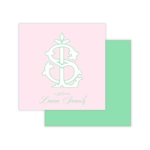 May include: A pink gift tag with a mint green monogram and the words "a gift from, Laura Samuels." A mint green envelope is partially visible behind the tag. The monogram is an ornate design of the letters "S" and "L".