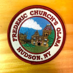 May include: Round embroidered patch with a white background and a maroon border. The patch features a detailed illustration of a building with a blue sky and a cloud. Text around the image reads "FREDERIC CHURCH'S OLANA HUDSON, NY."