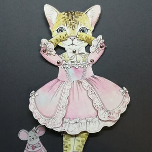 May include: A paper doll of a cat wearing a pink dress with lace trim and a bow. The cat is covering its eyes with its paws. A small paper doll of a mouse wearing a pink dress is standing next to the cat.