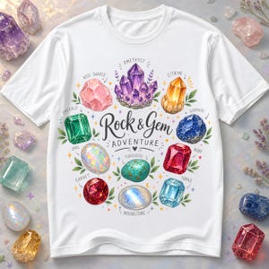 May include: A white t-shirt featuring a colorful graphic of various gemstones arranged in a circle. The text "Rock & Gem ADVENTURE" is printed in the center. The illustrated gems include amethyst, citrine, sapphire, ruby, topaz, moonstone, turquoise, opal, garnet, emerald, and rose quartz, each labeled with its name.