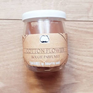 Peut inclure: Une bougie en verre dans un bocal avec une étiquette brune qui dit "Cotton Flower Bougie Parfumée Caramel au beurre salé".