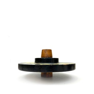 May include: A black wooden spinning top with a yellow design and a brown wooden top.