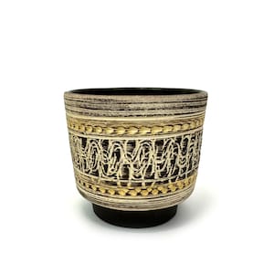 May include: A brown and white ceramic planter with a gold geometric design. The planter has a wide base and a slightly flared rim.