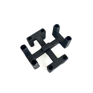 May include: A black plastic component with a unique, symmetrical design. It features four T-shaped arms, each with a circular opening at the end. The arms are connected at the center, forming a cross-like structure. The component is set against a white background.