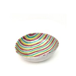 May include: A white ceramic bowl with a colourful striped design. The stripes are red, green, yellow, and white.