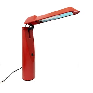 May include: A red desk lamp with a long, thin arm and a white light diffuser. The lamp has a cylindrical base and a black switch.