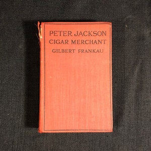 May include: A red book with the title "Peter Jackson Cigar Merchant" and the author "Gilbert Franka" printed on the cover.
