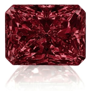Puede incluir: Una gema roja oscura de talla radiante, con una superficie facetada compleja. La gema es rectangular con bordes biselados, reflejando la luz para crear una exhibición brillante. El reflejo de la gema es visible debajo sobre una superficie blanca.