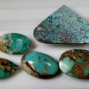 Puede incluir: Cinco piedras preciosas de turquesa de varias formas: una l&aacute;grima, un &oacute;valo, un tri&aacute;ngulo y otros dos &oacute;valos. Las piedras presentan un color turquesa vibrante con patrones de matriz marr&oacute;n y beige. Las piedras est&aacute;n pulidas y tienen un acabado brillante.