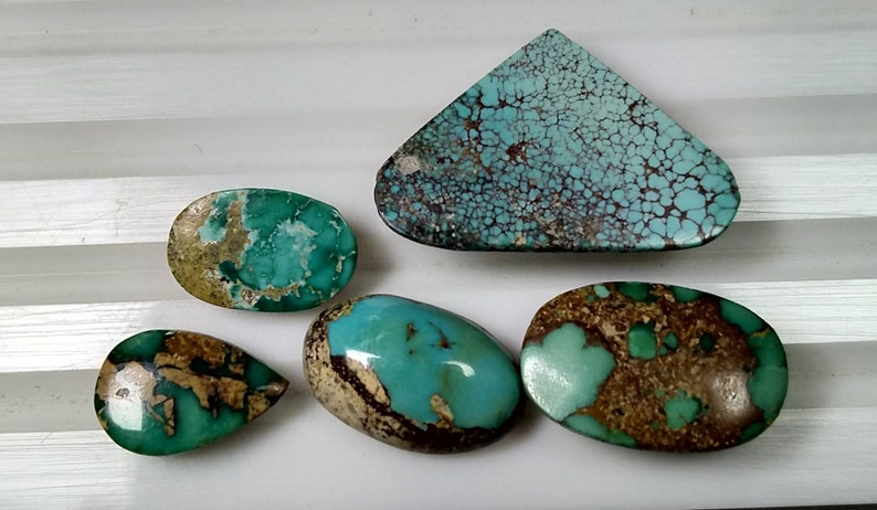 Puede incluir: Cinco piedras preciosas de turquesa de varias formas: una l&aacute;grima, un &oacute;valo, un tri&aacute;ngulo y otros dos &oacute;valos. Las piedras presentan un color turquesa vibrante con patrones de matriz marr&oacute;n y beige. Las piedras est&aacute;n pulidas y tienen un acabado brillante.
