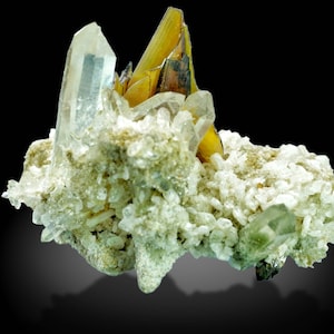 May include: A cluster of natural crystals, featuring a large, clear quartz crystal alongside golden-yellow and clear crystals. The crystals are set against a backdrop of smaller, white and light green crystals, creating a striking contrast. The background is black.