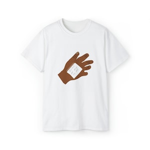 Puede incluir: Camiseta blanca con una ilustración de una mano marrón que lleva un vendaje blanco con el texto "Please be nice to me" escrito en él.