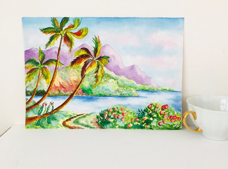 May include: Watercolor painting of a tropical landscape with palm trees, a blue lake, and purple mountains in the background. Two green parrots are perched on a palm tree branch.