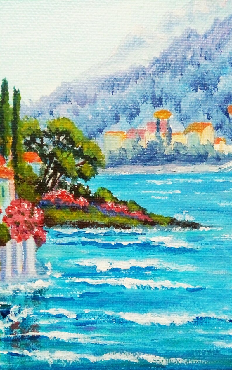 May include: A painting depicting a seascape with a small town in the background. The town is situated on a hill and features white buildings with orange roofs. The foreground showcases a small island with green trees and pink flowers. The water is a vibrant blue with white waves.