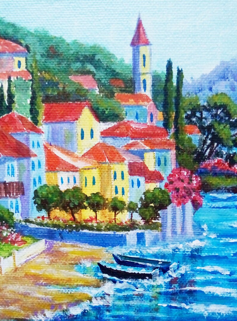May include: A painting depicting a colourful seaside village with red-tiled roofs, a tall white tower, and two boats in the water. The scene is painted in a bright, impressionistic style.