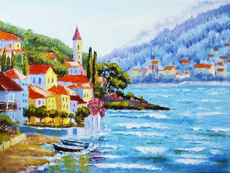 May include: A painting depicting a small town nestled on a hillside overlooking a blue expanse of water. The town features red-roofed buildings and a tall white church spire. The water is choppy and a small boat is visible in the foreground.
