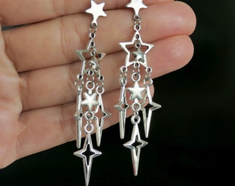 May include: Silver dangle earrings with a cascading design of star shapes. The earrings are long and feature multiple stars of varying sizes.