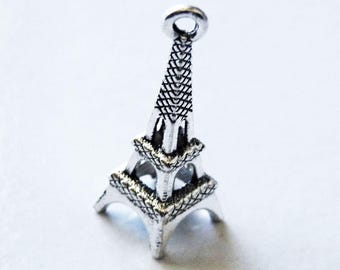 May include: A silver-colored Eiffel Tower charm with intricate detailing. The charm has a loop at the top for attaching to a necklace or bracelet. The design includes detailed cross-hatching and open spaces.