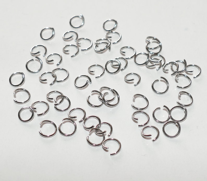 May include: A large quantity of silver jump rings, a type of jewelry finding used for connecting chains, cords, and other jewelry components.