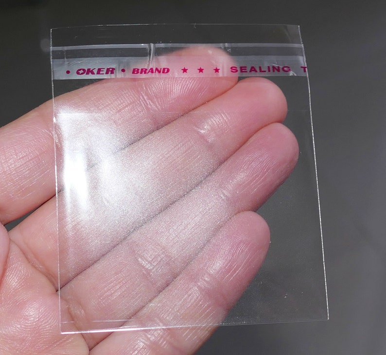 Puede incluir: Bolsa de pl&aacute;stico transparente con un sello rojo que dice "OKER BRAND SEALING TAPE".