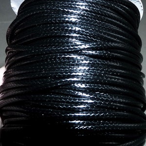 May include: A spool of black waxed cord. The cord is tightly wound and has a glossy finish.