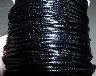 May include: A spool of black waxed cord. The cord is tightly wound and has a glossy finish.