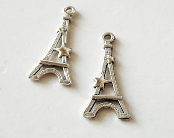 Puede incluir: Dos encantos de plata de la Torre Eiffel con estrellas doradas. Los encantos son perfectos para agregar un toque parisino a las joyas o las manualidades.