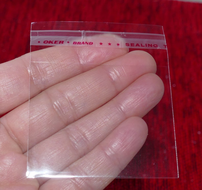 Puede incluir: Bolsa de pl&aacute;stico transparente con una banda de sellado t&eacute;rmico roja que dice "OKER BRAND *** SEALING".