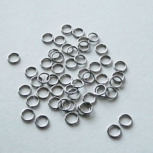 Op de afbeelding: Een stapel zilveren springringen, een soort sieradenbevestiging die wordt gebruikt om kettingen, koorden en andere sieradencomponenten te verbinden.